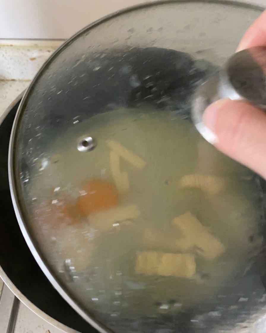 Un couvercle en verre posé sur une poêle, retenant la vapeur à lintérieur pour cuire les œufs et faire fondre le fromage.