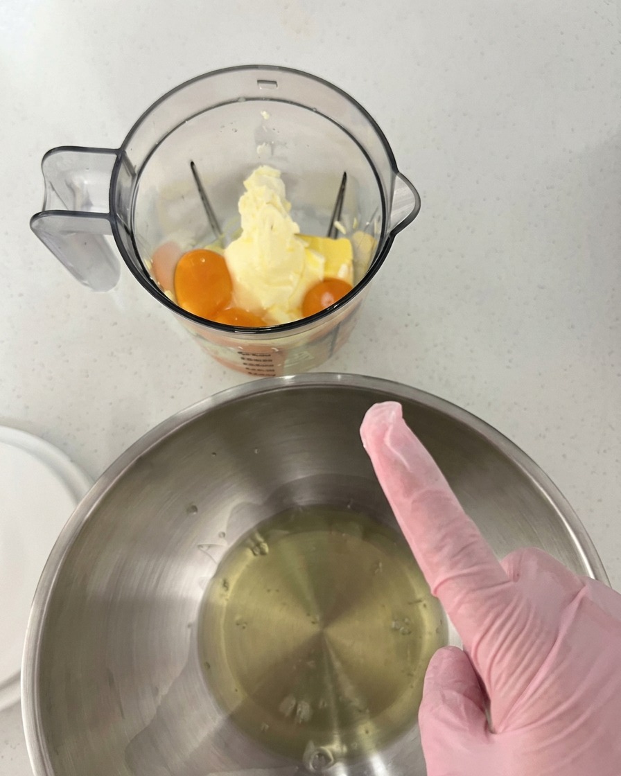 Jaunes dœufs, beurre et fromage à la crème dans le bol transparent dun blender, à côté dun saladier en inox contenant les blancs dœufs.