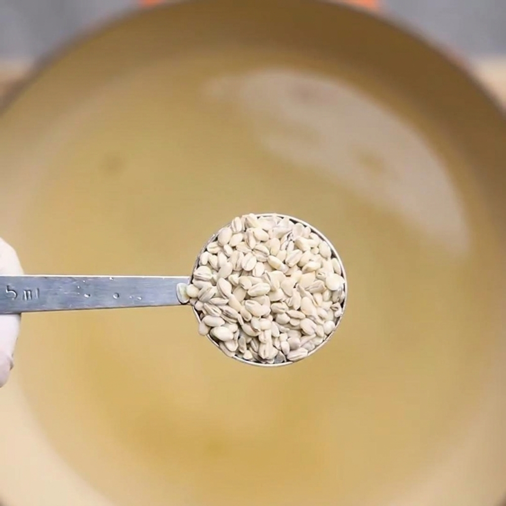 Une cuillère prélevant de lorge cuite dans une casserole deau bouillante.