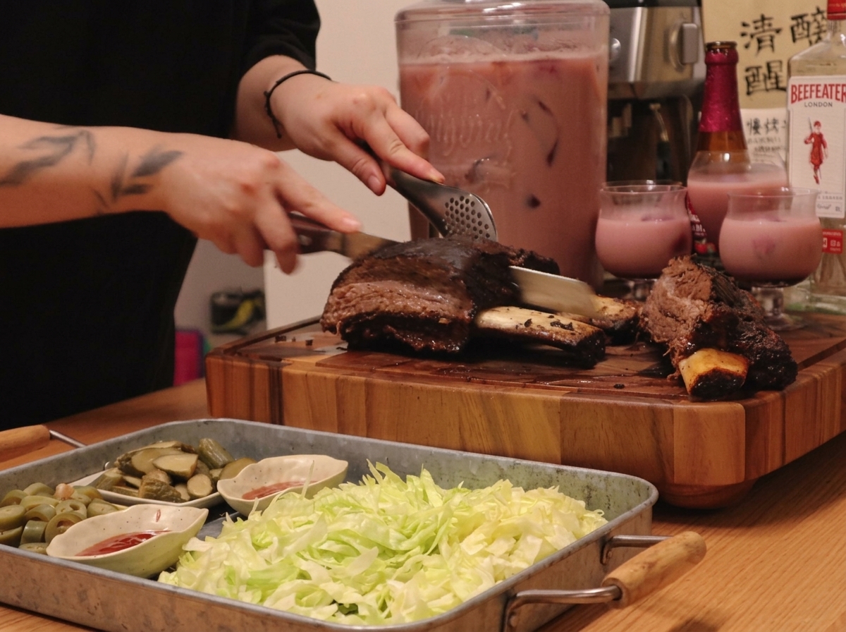 Un plateau présentant des travers de bœuf tranchés avec des accompagnements de laitue, cornichons et des bols de sauce rouge.
