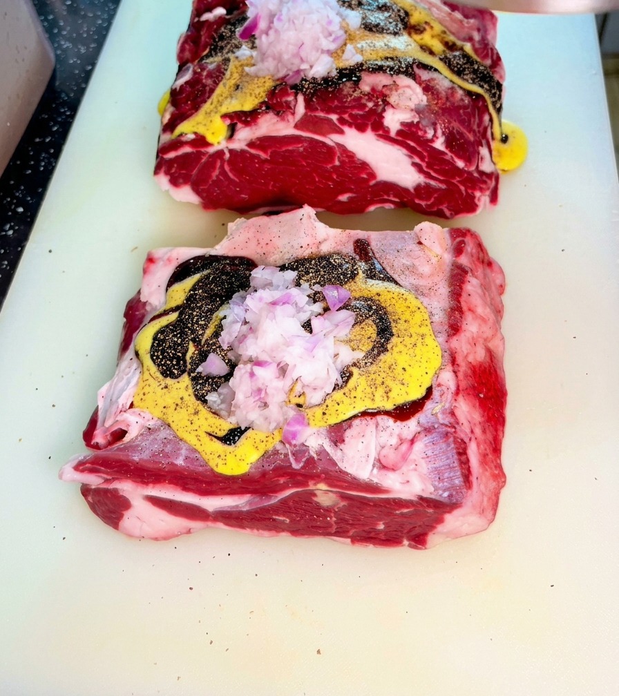 Bœuf cru recouvert de sauces et doignon rouge haché sur une planche.