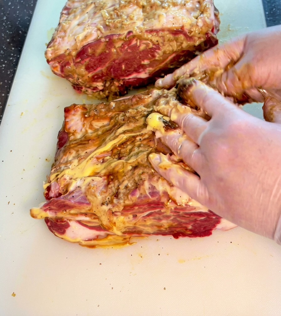 Mains massant le mélange dépices et de sauces dans la viande de bœuf.