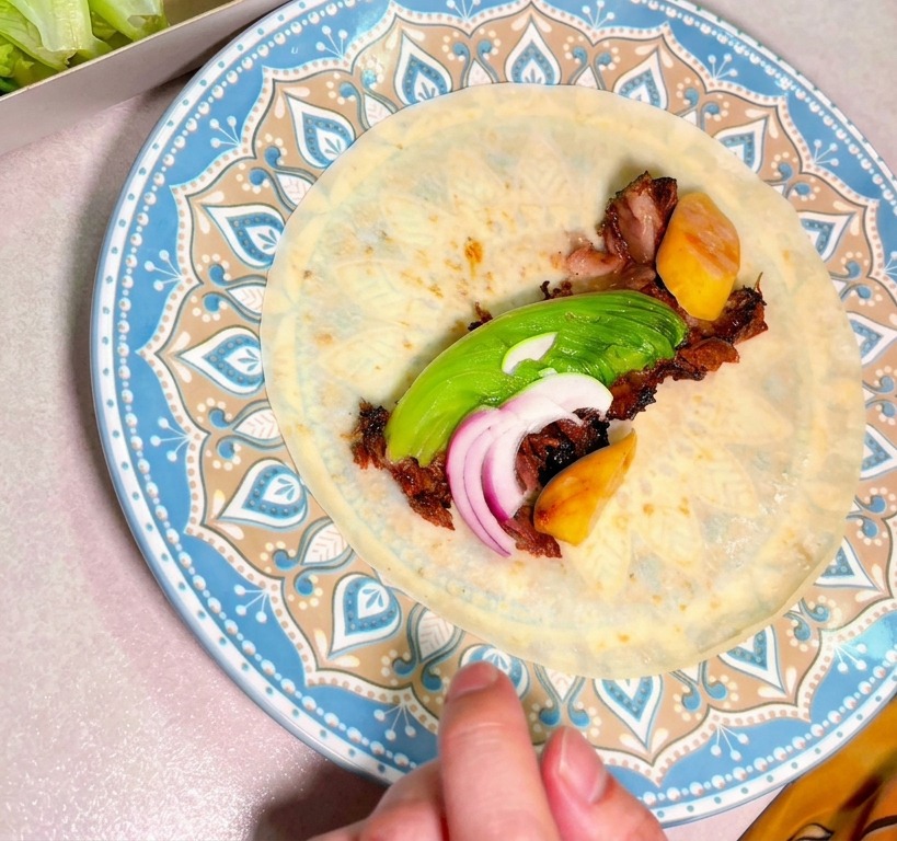Bœuf fumé haché avec avocat et oignons rouges au centre dune tortilla.