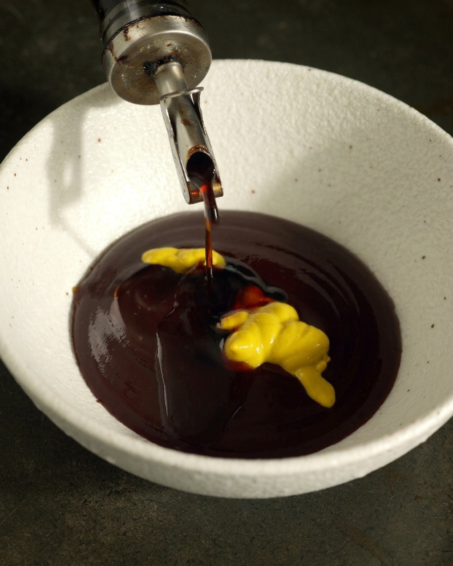 Sauce soja claire versée dans un bol contenant de la sauce BBQ et un filet de moutarde jaune.