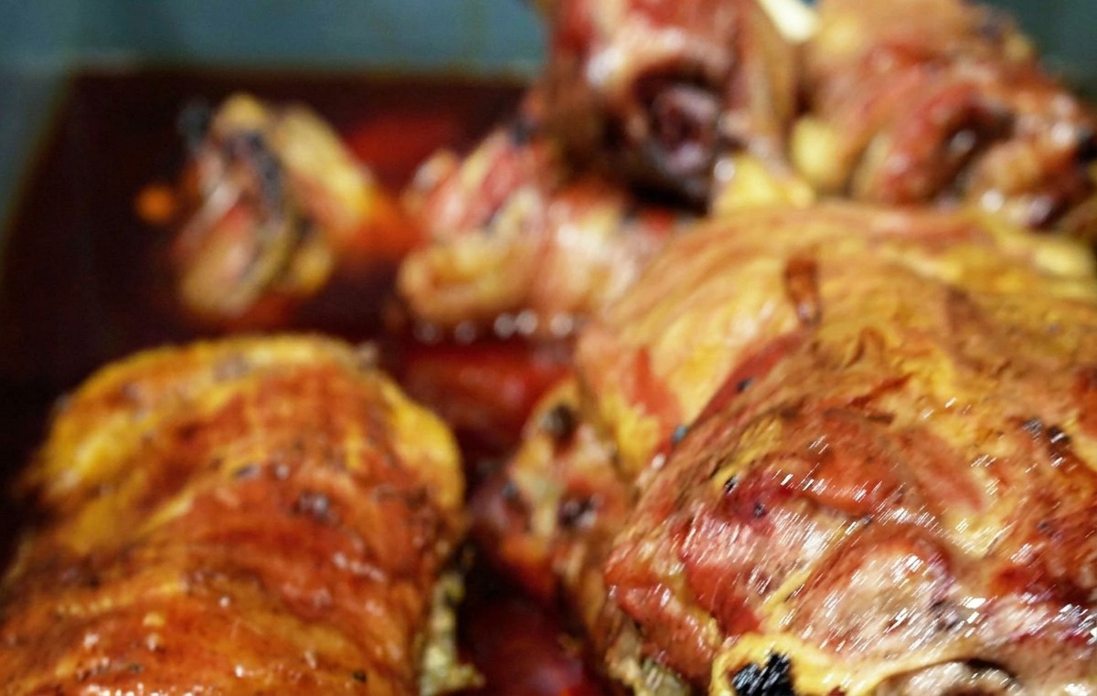 Plusieurs morceaux de bœuf fumé immergés dans une marinade liquide brun-rougeâtre dans un bac bleu.