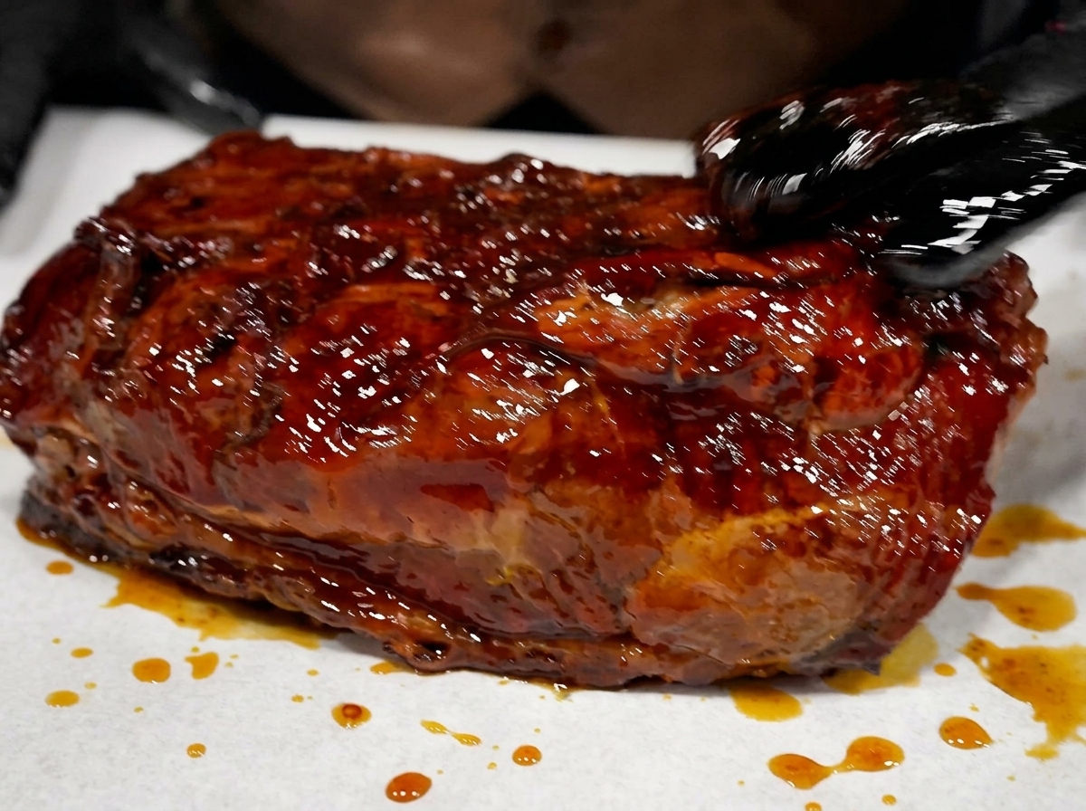 Un morceau de bœuf fumé brillant de marinade reposant sur une feuille daluminium.
