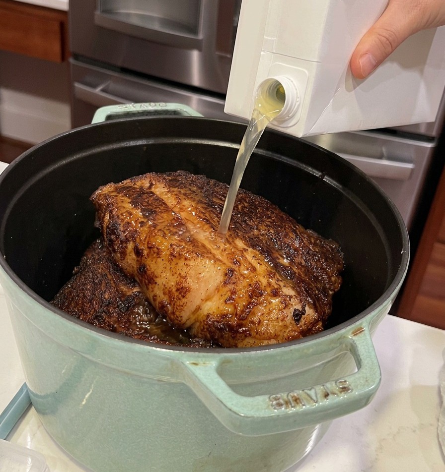 Verser du bouillon de volaille dans la cocotte contenant les morceaux de bœuf.