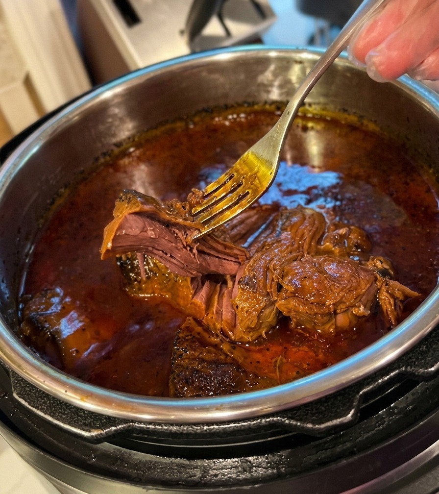 Une fourchette effilochant sans effort un morceau de bœuf très tendre dans la cocotte.
