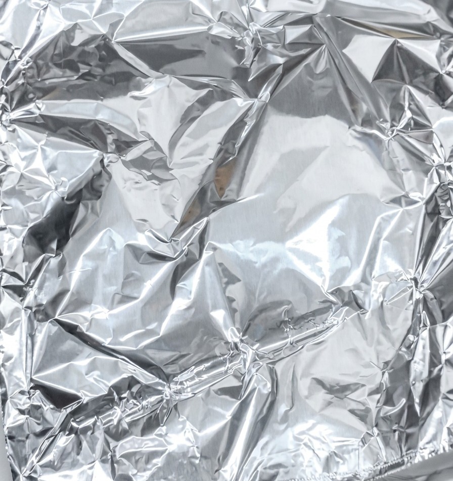Gros plan sur la fermeture hermétique dune feuille daluminium enveloppant le porc mariné.