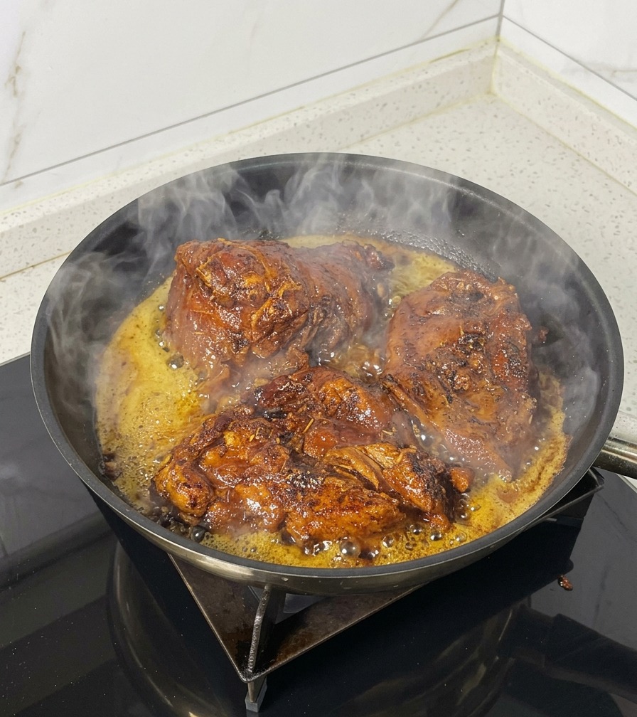 Trois morceaux de porc saisissant dans une poêle noire avec de la vapeur et de lhuile frémissante.