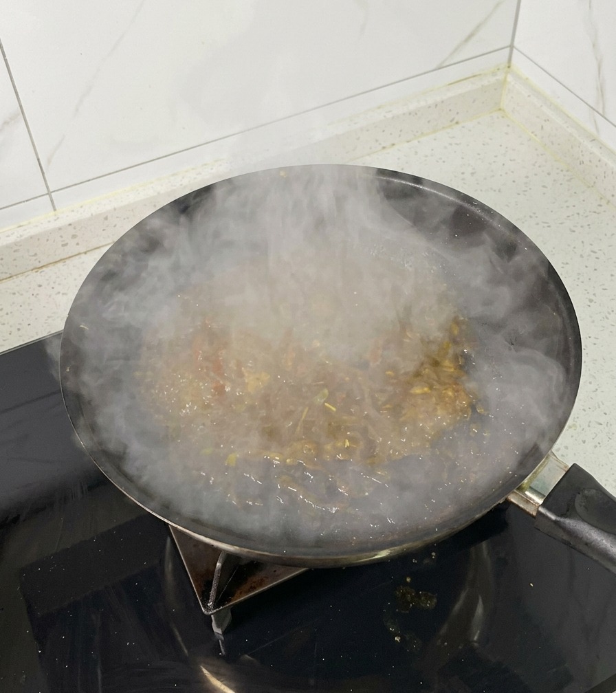 Une poêle sur le feu remplie dun jus de braisage bouillonnant et épais dégageant de la vapeur.