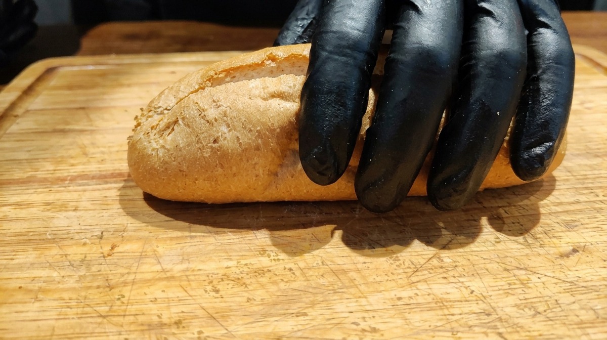 Baguette de blé complet tranchée dans la longueur sur une planche en bois.