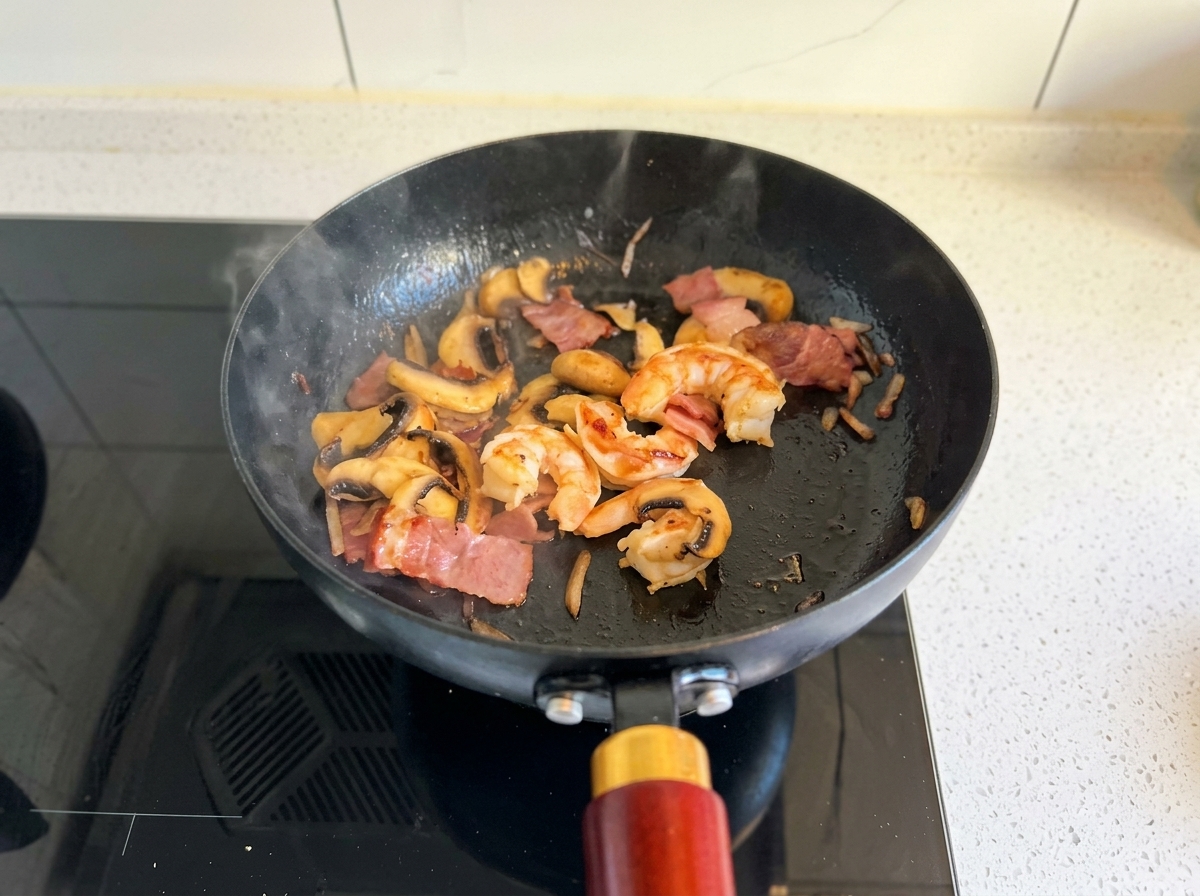 Cuisson des crevettes, lardons et champignons jusquà ce que les crevettes soient roses et opaques.