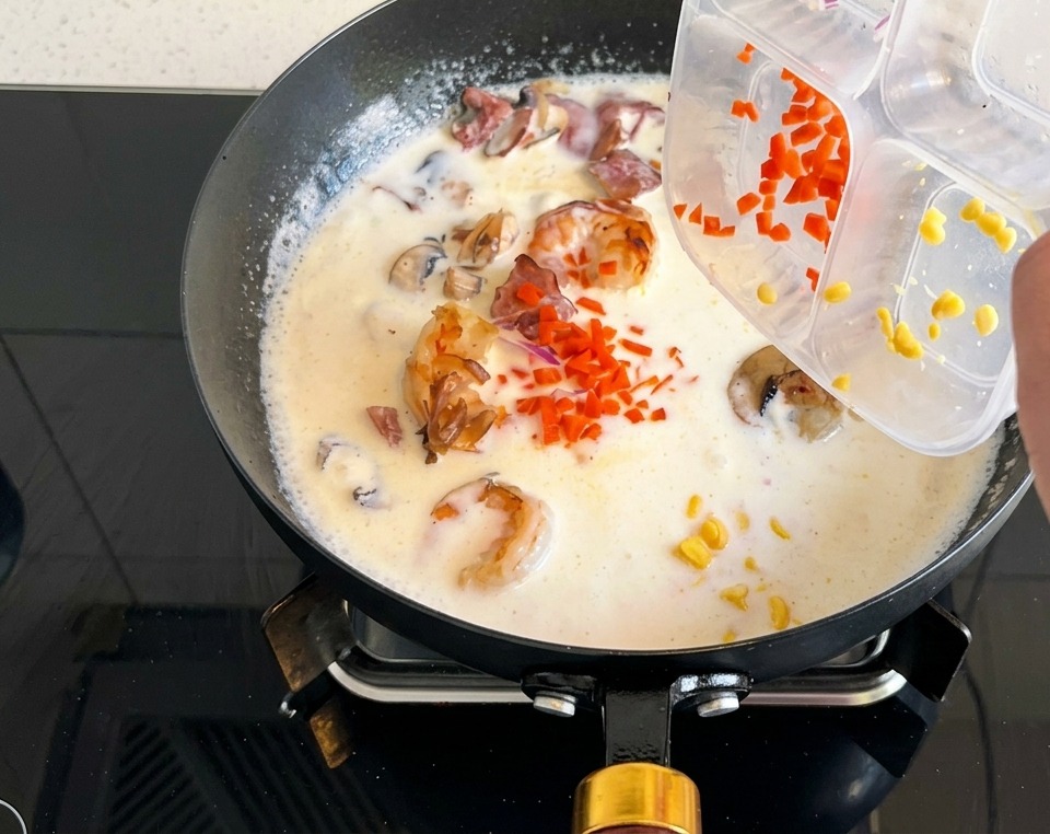 Dés de carottes et maïs doux versés dans la soupe crémeuse.
