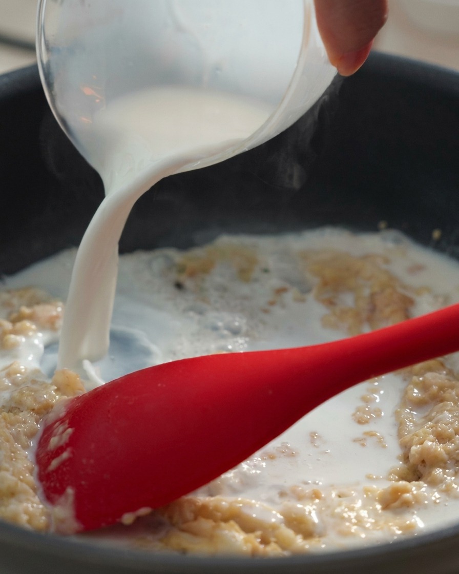 Lait versé dans le mélange beurre-farine tout en remuant vigoureusement.