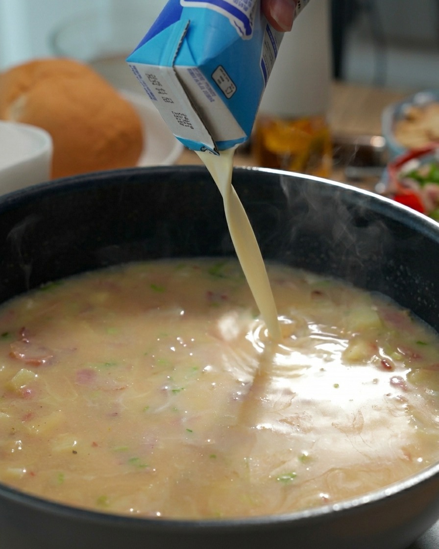 Crème liquide versée dans la base de chaudrée frémissante.