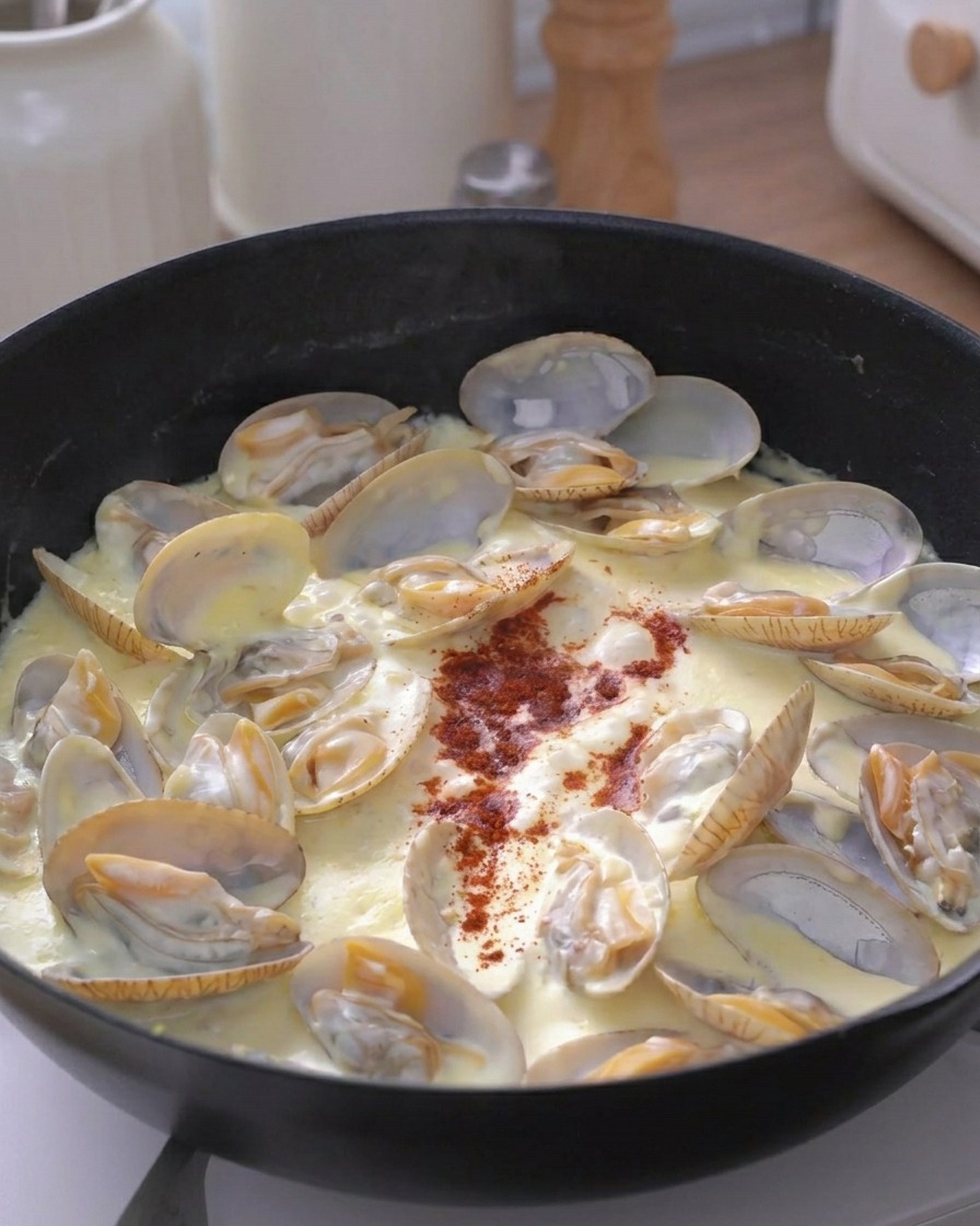 Une pincée de piment rouge saupoudrée au centre de la poêle de palourdes à la crème.
