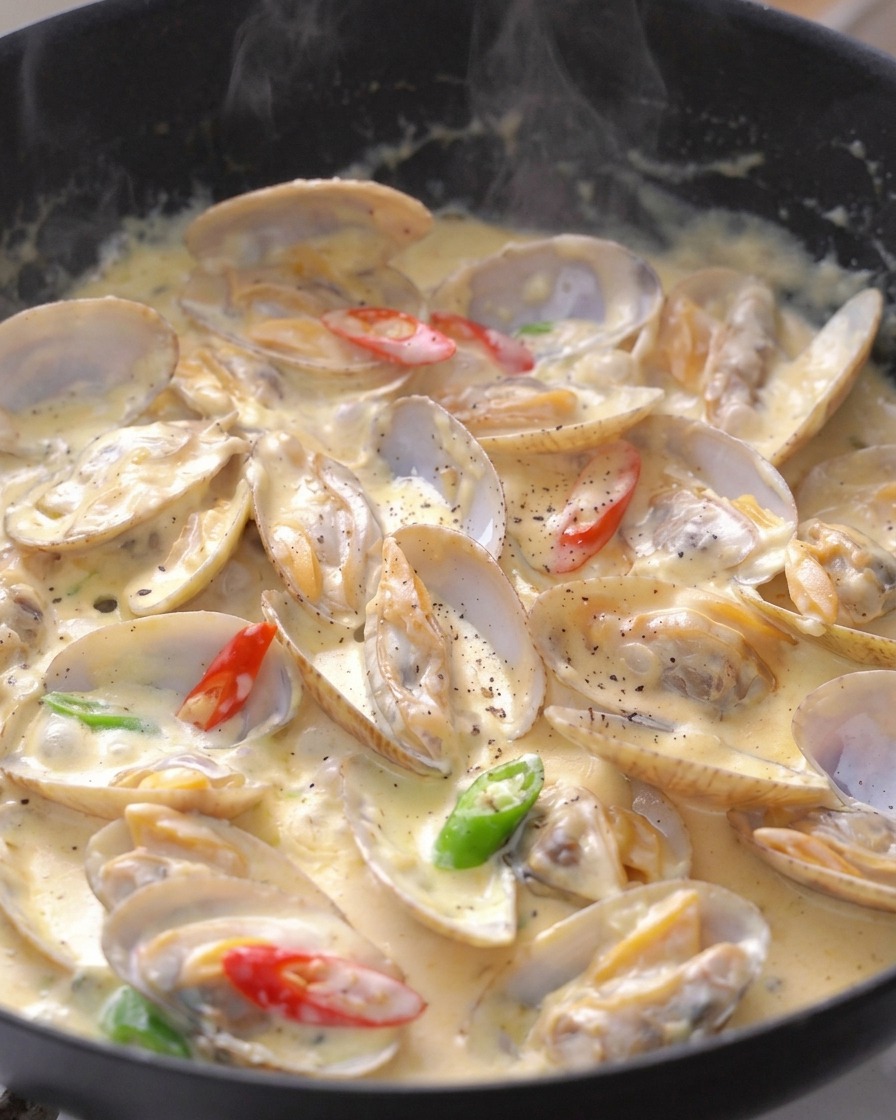 Palourdes à la crème garnies de rondelles de piments verts et rouges et de poivre noir.