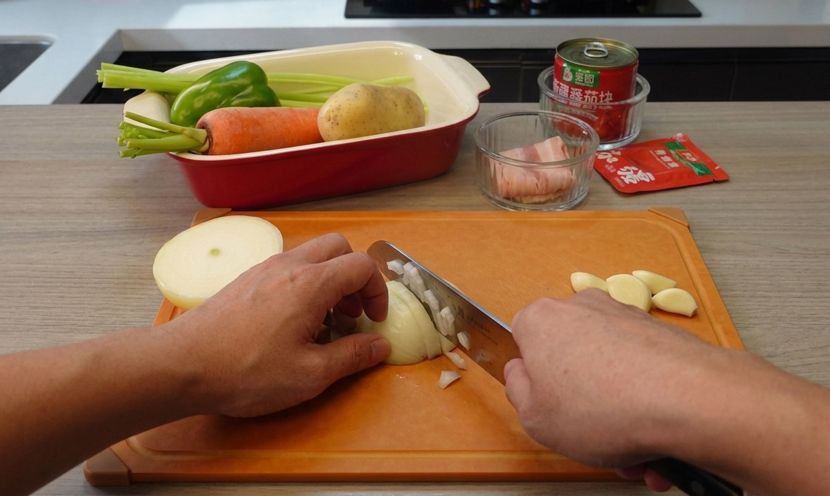 Mains tenant un couteau de cuisine et hachant finement un oignon blanc sur une planche à découper orange, avec des gousses dail à côté.