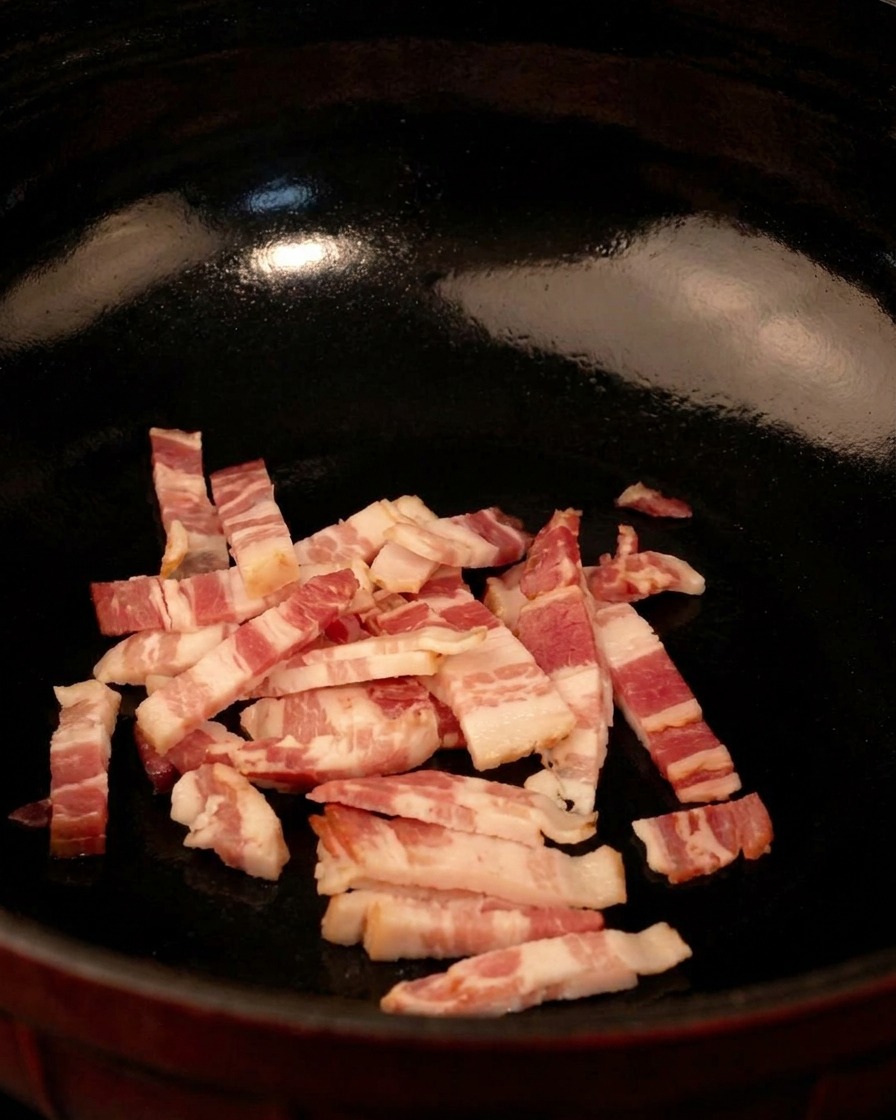 Lanières de bacon crues dans une poêle noire prêtes à cuire à feu moyen.