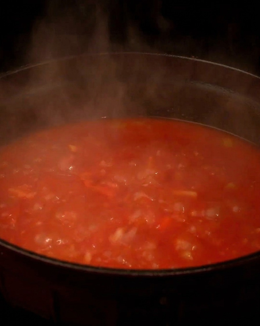 Marmite fumante de soupe à la tomate bouillonnant sur la cuisinière.