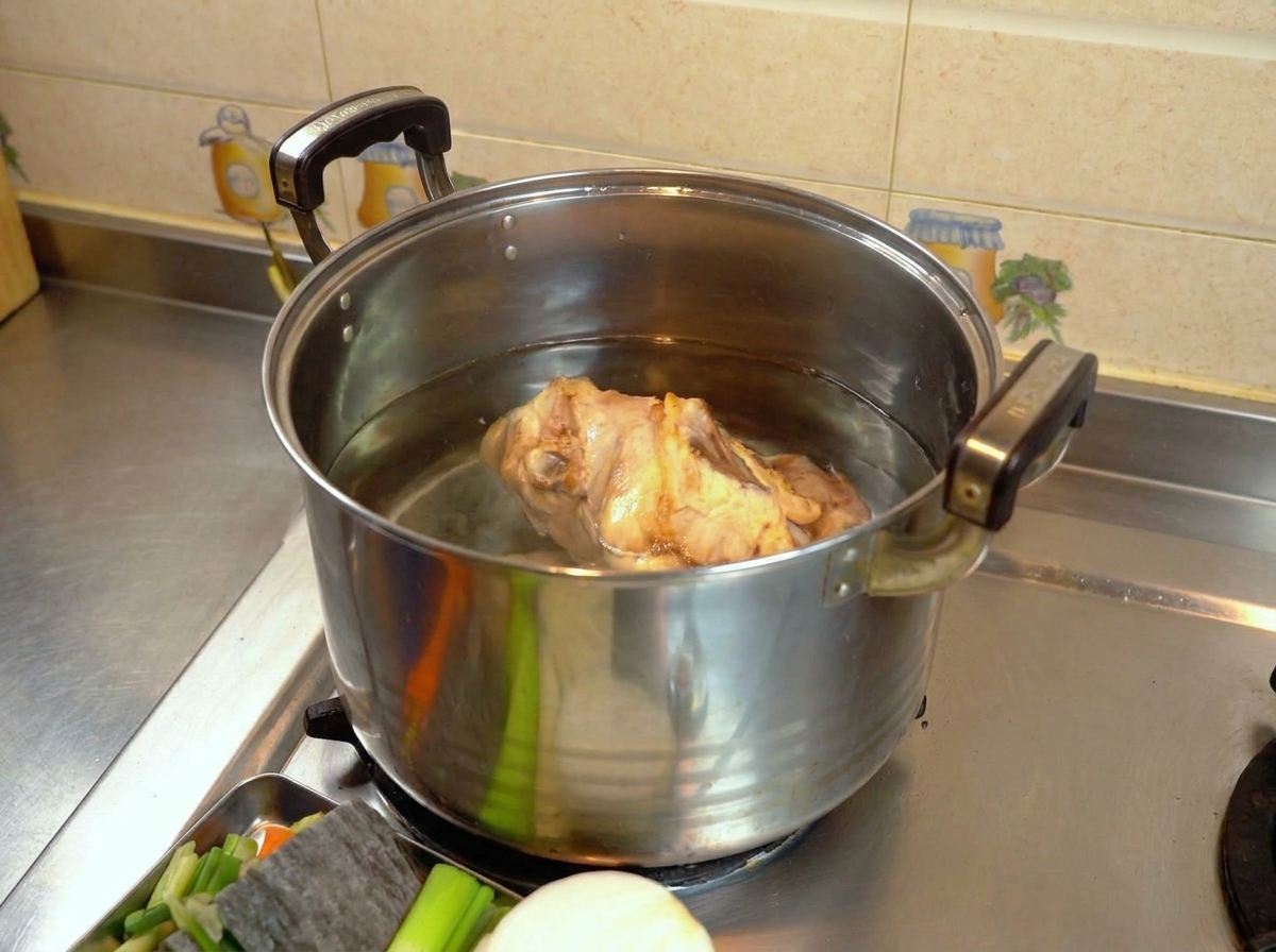 Une carcasse de poulet blanchie dans une grande marmite remplie deau claire sur une cuisinière.