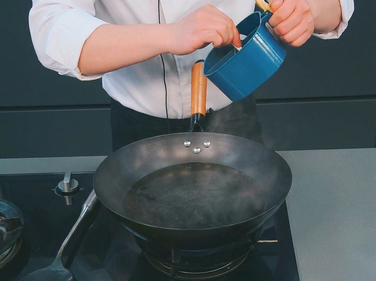 Un chef ajoutant une petite cuillerée de sel dans un wok deau bouillante fumante.
