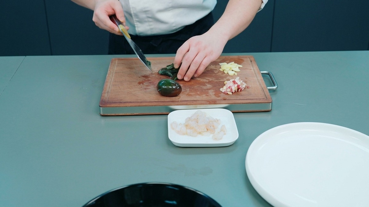 Chef coupant un œuf de cent ans sombre sur une planche en bois à côté de tranches dail.