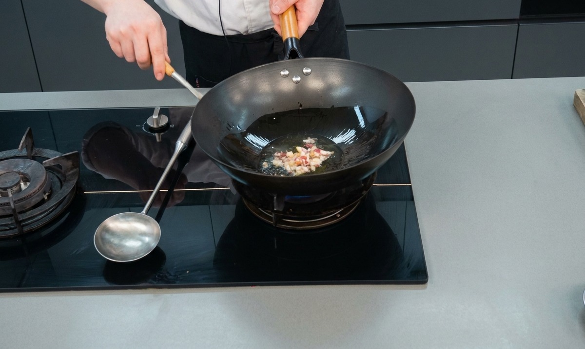 Dés de viande et ail crépitant dans lhuile chaude à lintérieur dun wok noir.