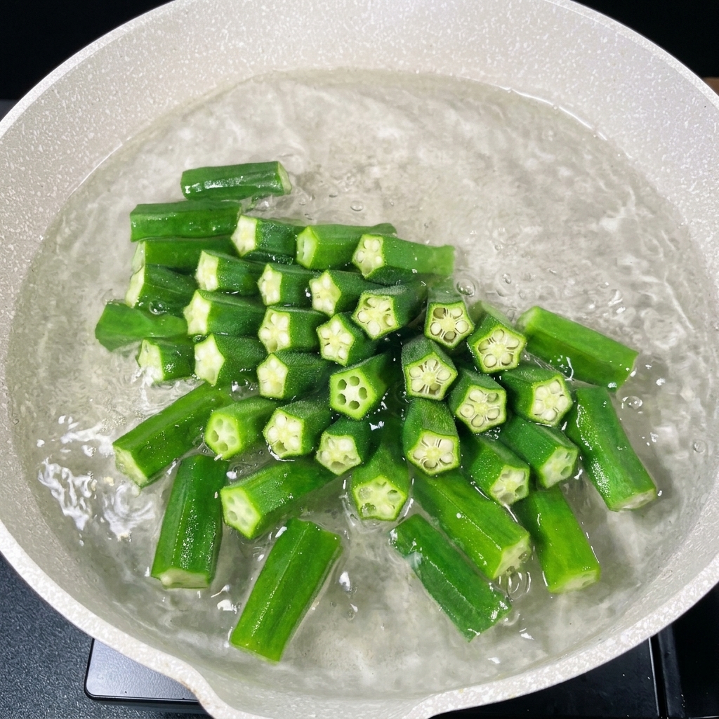 Morceaux de gombos coupés, vert vif, bouillant dans une casserole deau chaude.