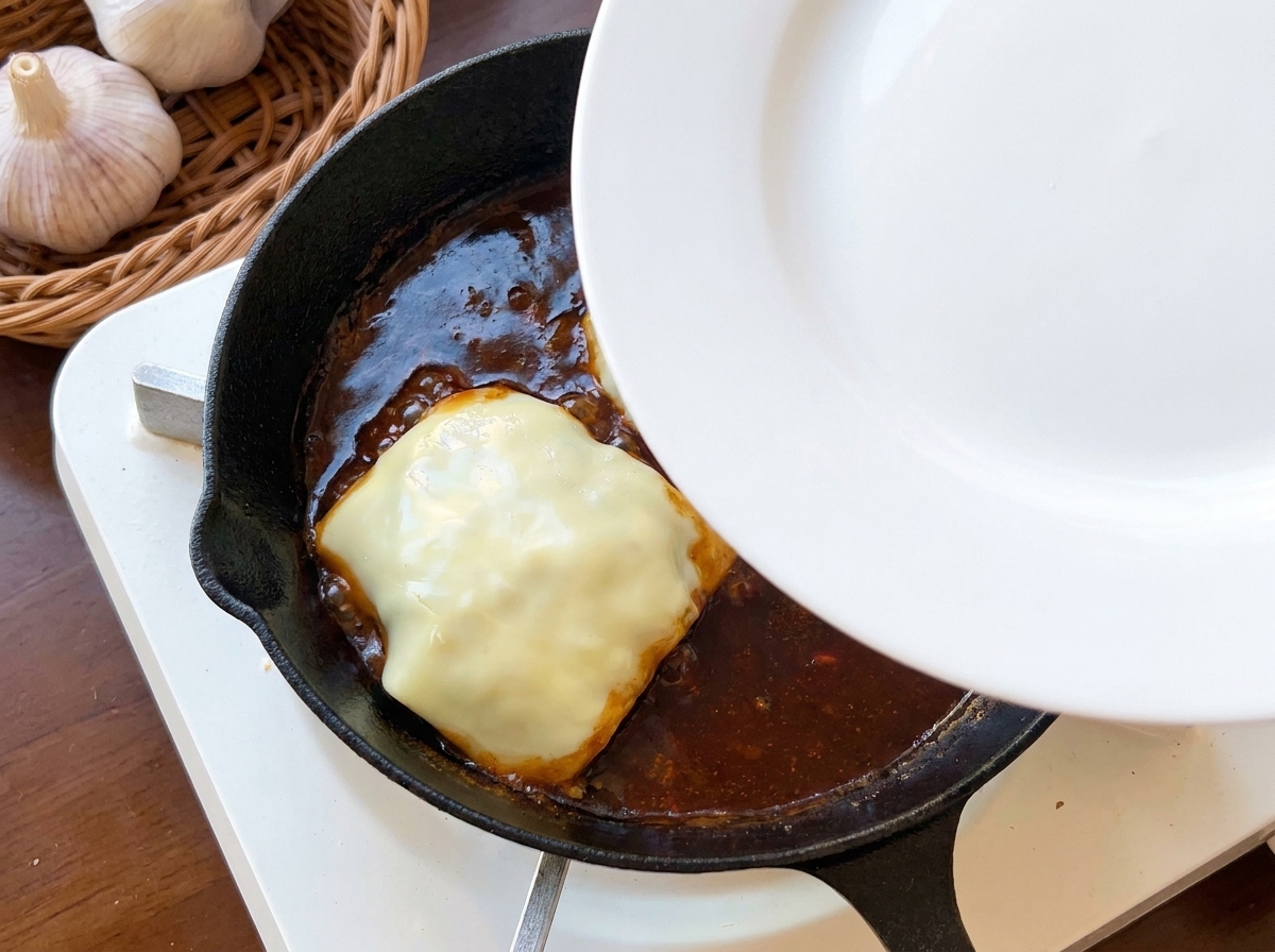 Une assiette blanche utilisée comme couvercle sur une poêle en fonte.