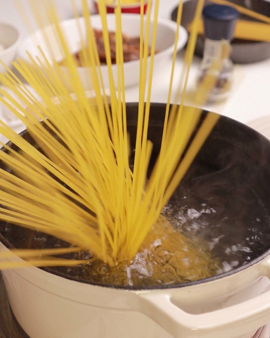 Des spaghetti secs plongés dans une casserole deau bouillante.