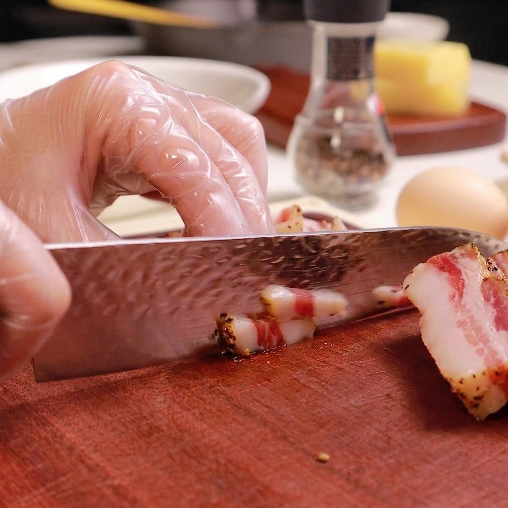 Gros plan dun couteau découpant des tranches de guanciale en petits bâtonnets.