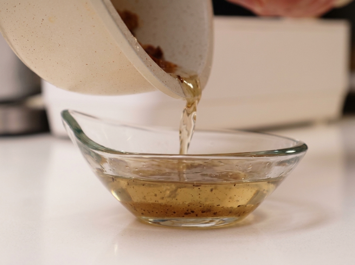 Versage du gras de porc fondu dune poêle vers un bol en verre.
