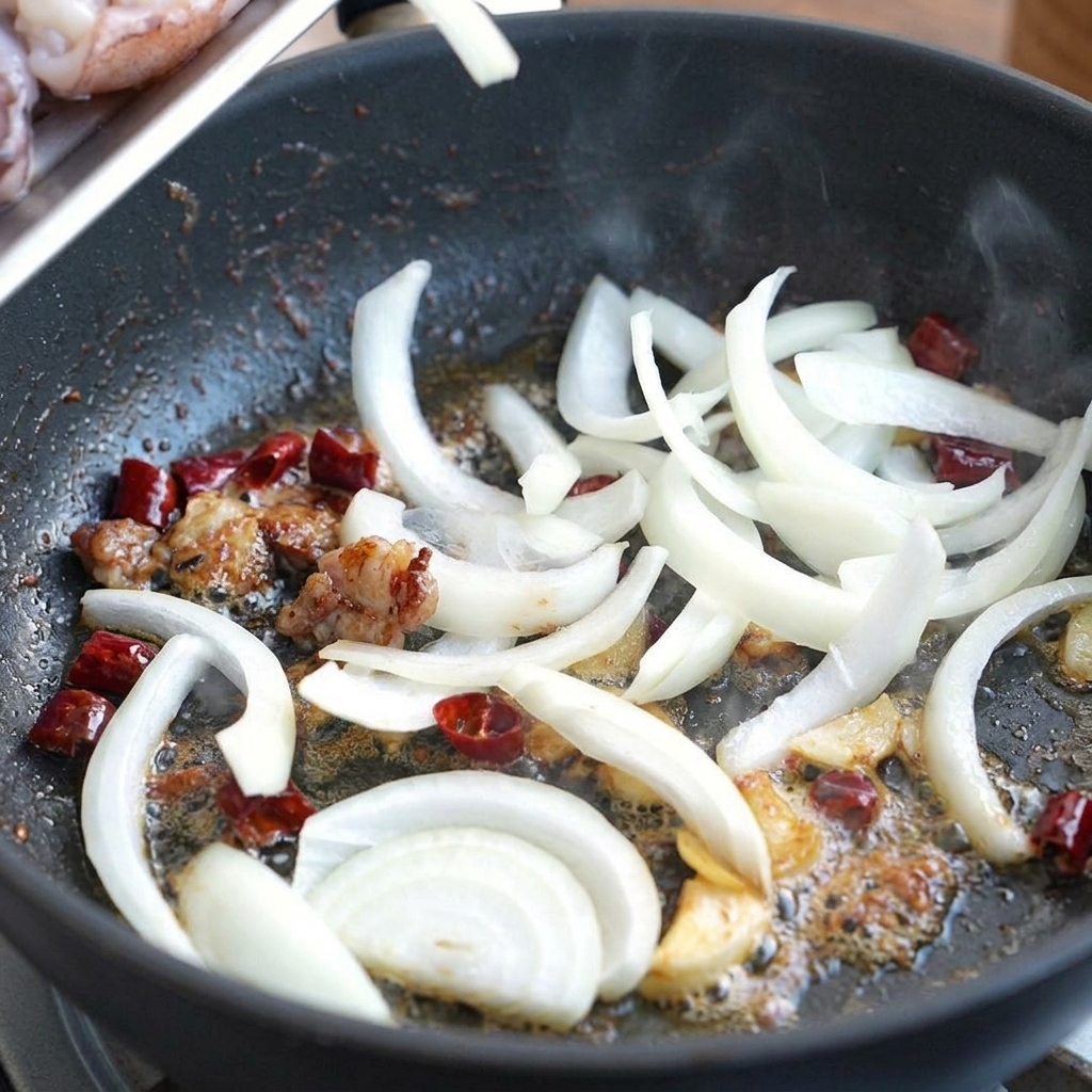 Oignons blancs émincés sautant dans lhuile parfumée avec les piments et lail.
