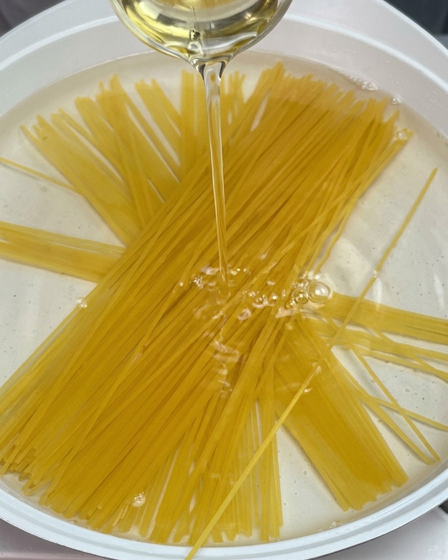 Spaghetti secs immergés dans une casserole deau avec un filet dhuile.