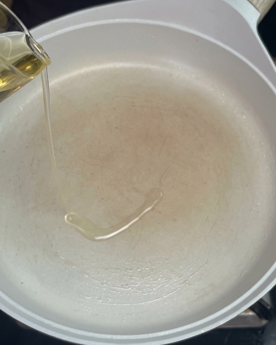 Huile de cuisson versée dans une poêle blanche préchauffée.
