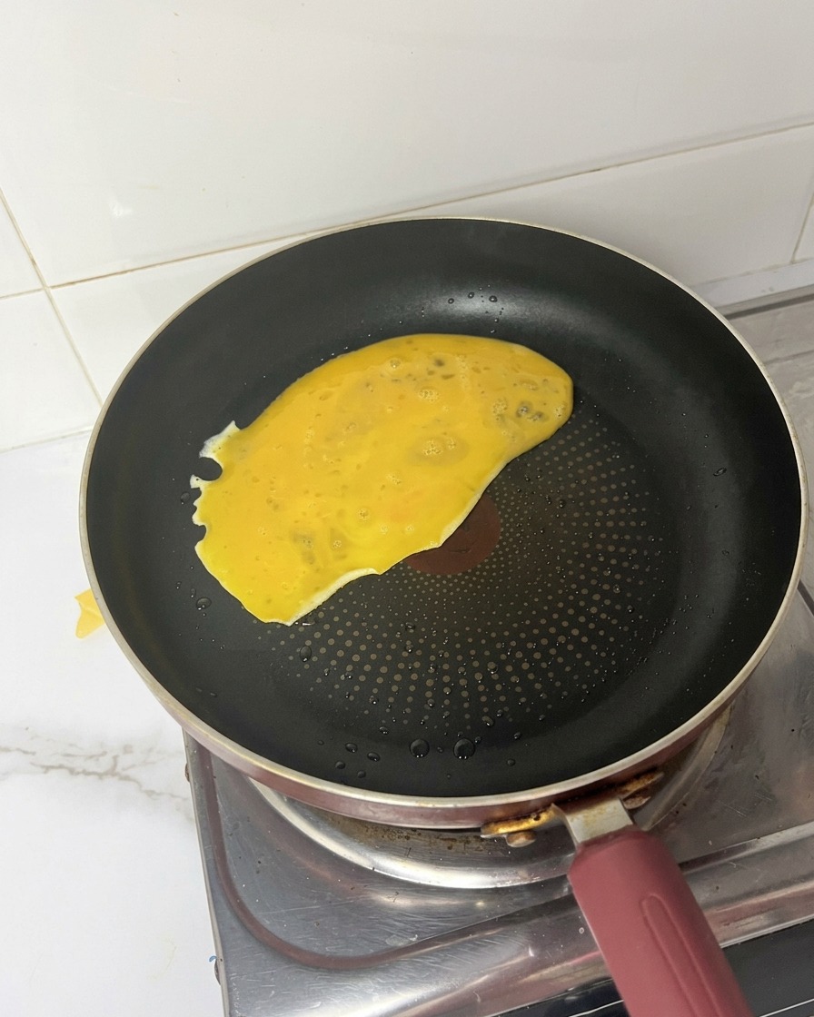 Mélange dœufs battus versé et sétalant dans une poêle chaude.