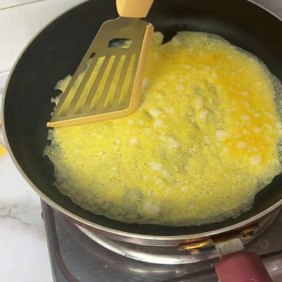 Une fine omelette jaune coupée en quatre morceaux à laide dune spatule métallique.
