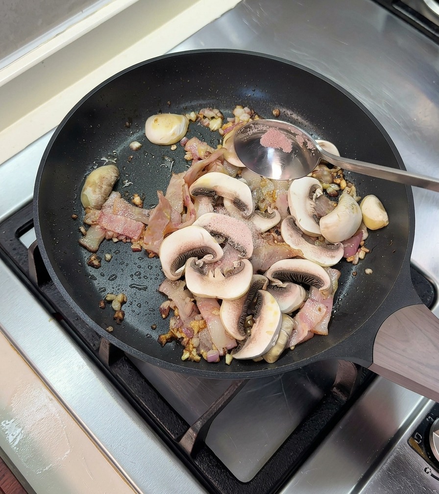 Ajout dune cuillerée de sel rose dans la poêle contenant les lardons cuits et les champignons.