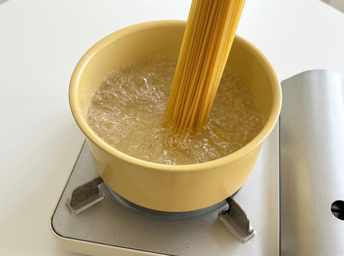 Spaghettis secs plongés dans une casserole deau bouillante.
