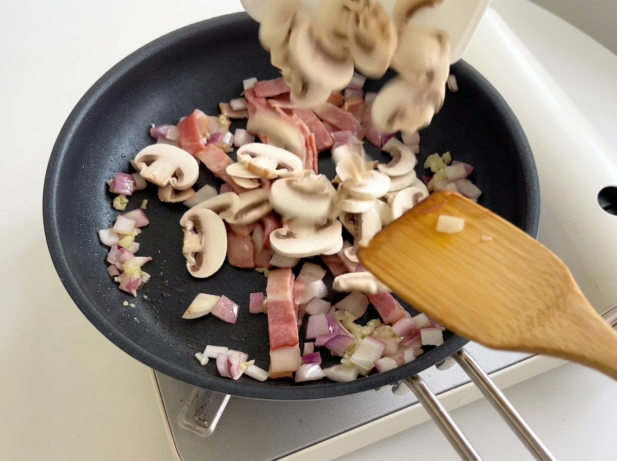 Lamelles de champignons ajoutées à la préparation de bacon et oignons.