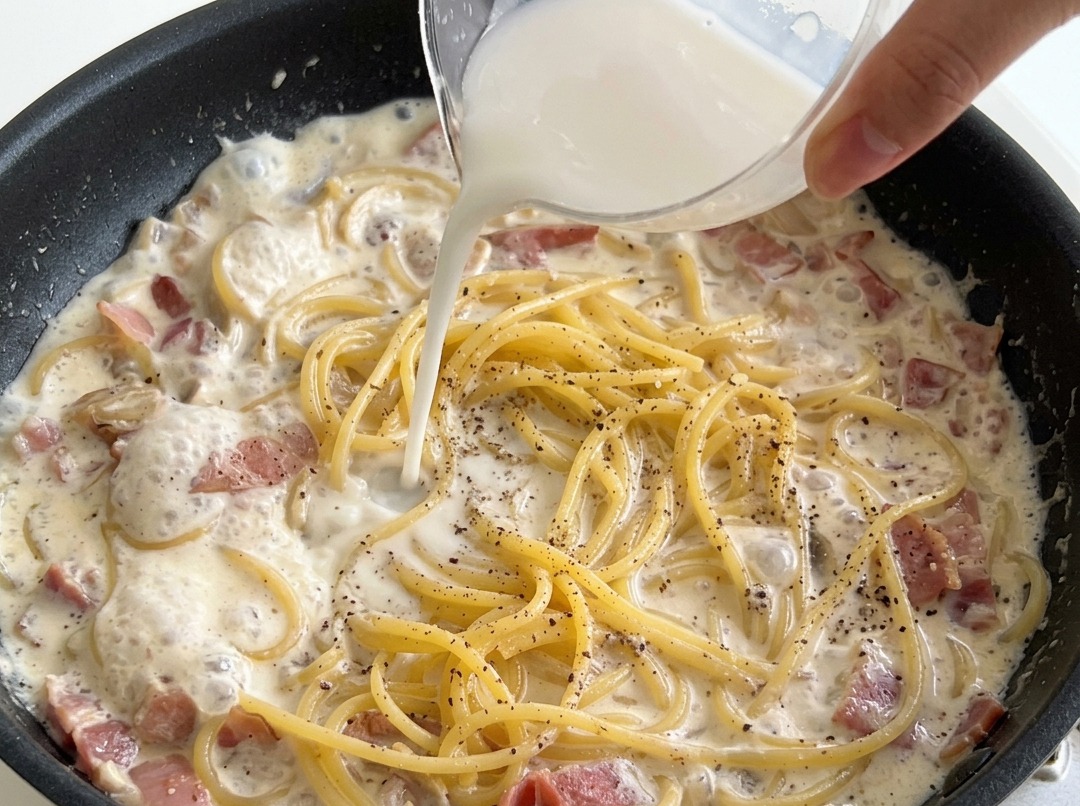 Versement dun mélange eau et fécule sur les spaghettis en sauce.