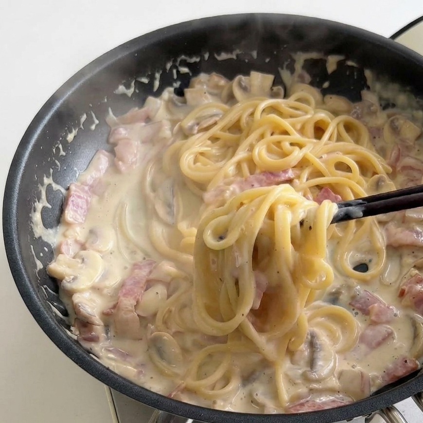 Baguettes mélangeant les spaghettis dans la sauce épaisse et bouillonnante.