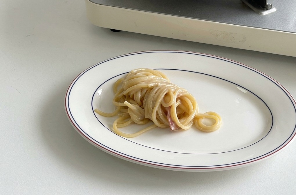 Dôme de spaghettis crémeux au centre dune assiette blanche.