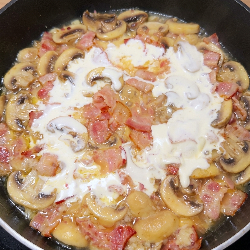 Crème liquide sécoulant dans la poêle et se mélangeant aux ingrédients rissolés.