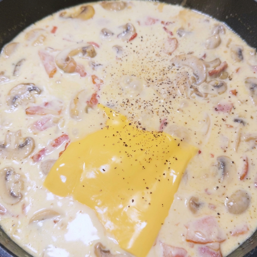 Tranche de fromage fondant dans la sauce crémeuse, saupoudrée de poivre noir fraîchement moulu.