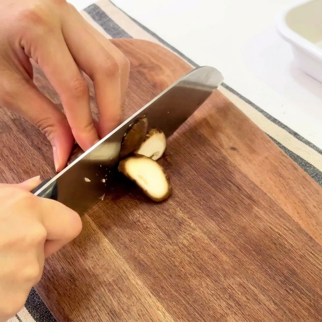 Mains coupant des champignons shiitake frais sur une planche en bois.