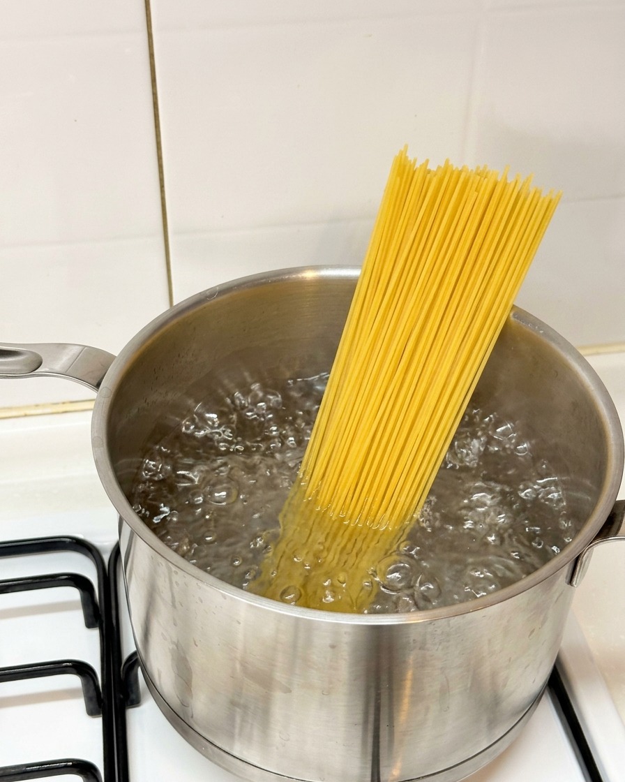 Spaghettis secs plongés dans une casserole deau bouillante.