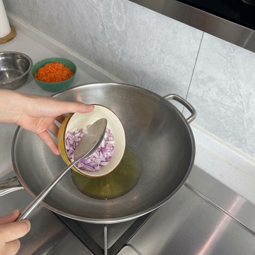 Une main versant des oignons rouges en dés dans un wok avec de lhuile chaude.